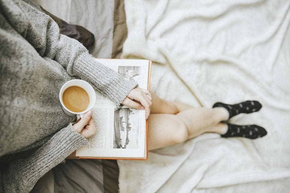 women holding a coffee cup and book