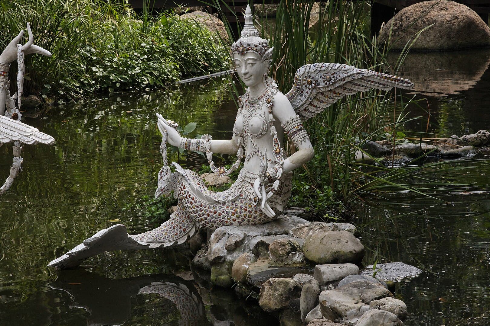 Half human half mermaid statue on a pond