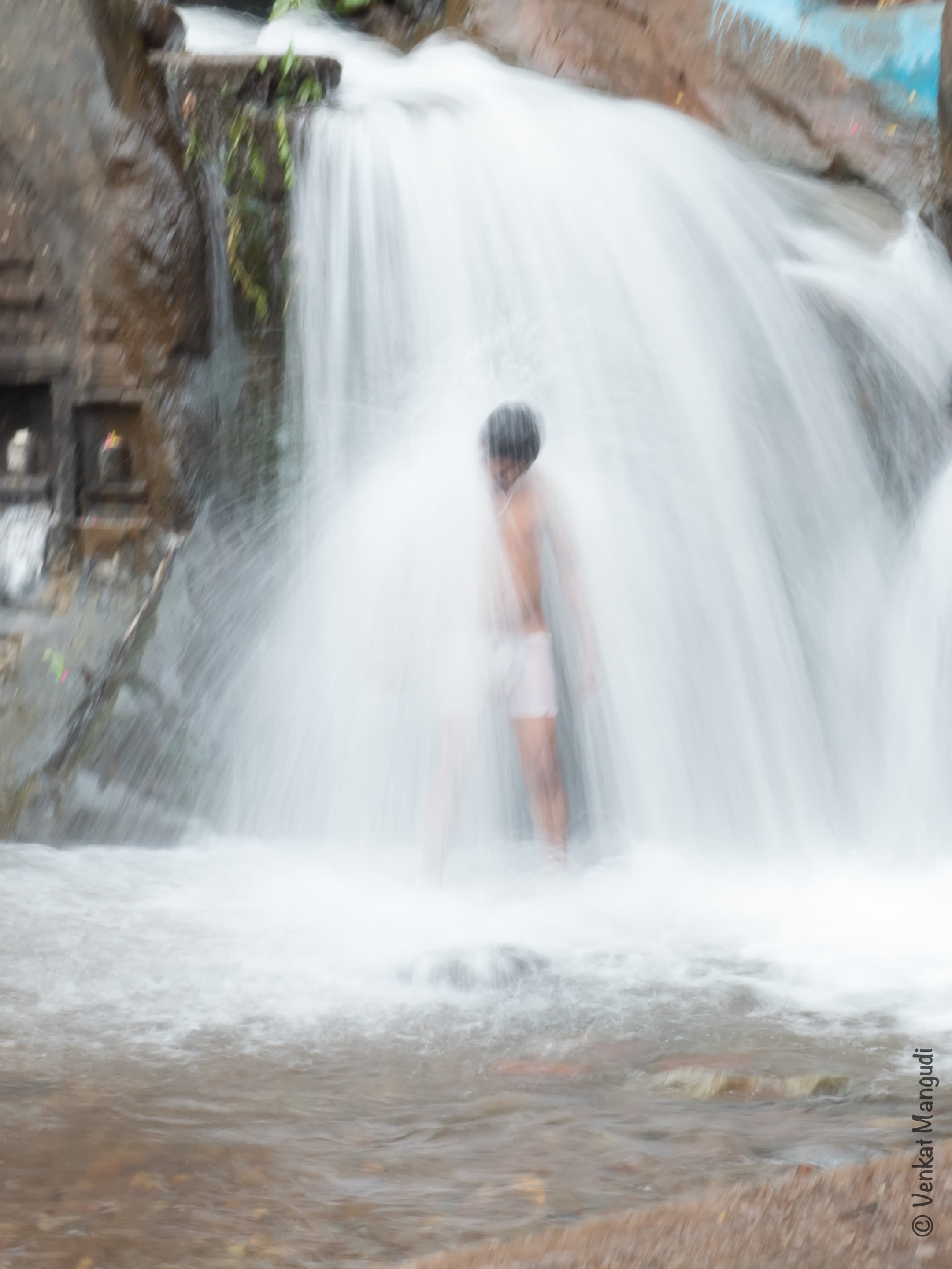 A person taking a dip in the Kallathigiri waterfall