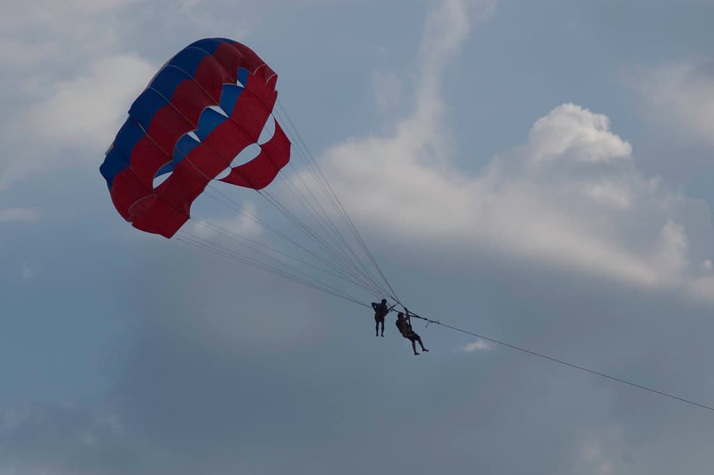 Brightly colored paragliding parachutes against the blue sky