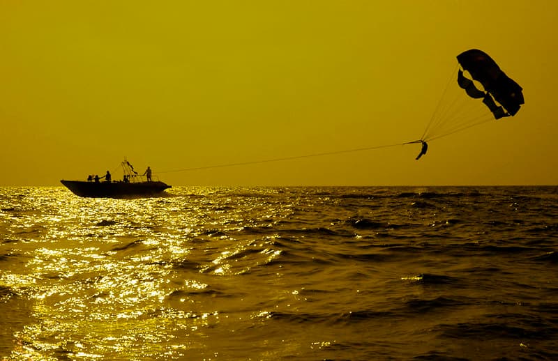 A thrill-seeker soaring above Calangute Beach while parasailing