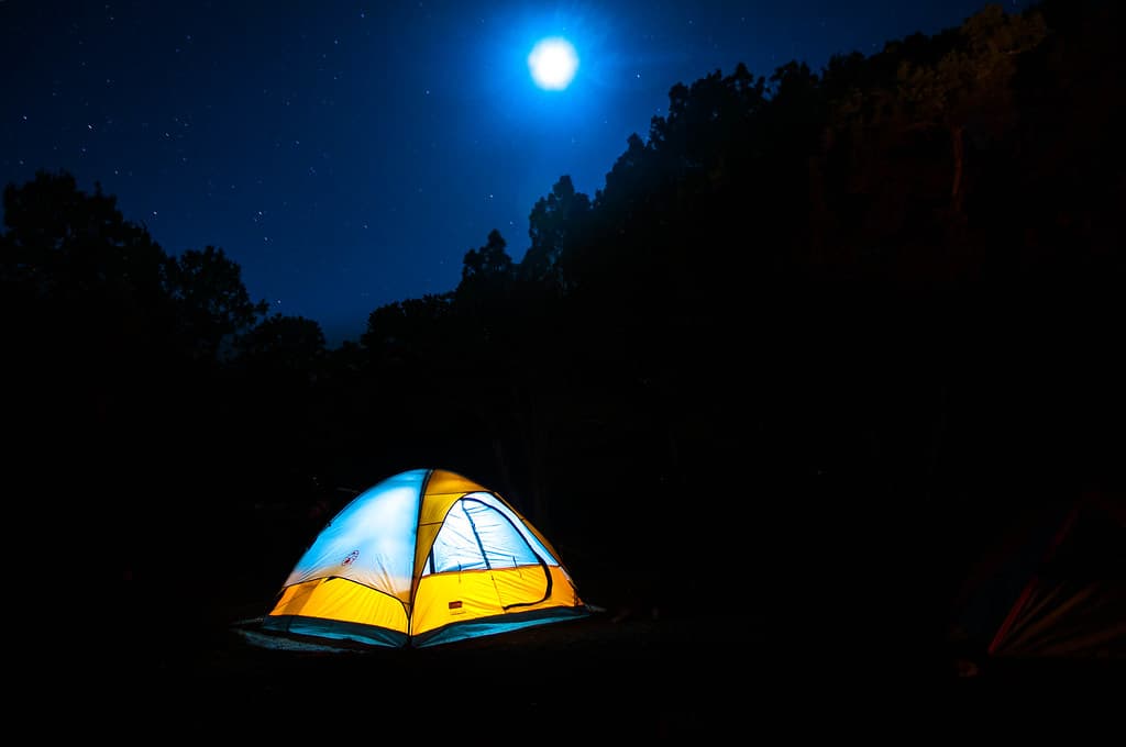 Night camping with a lit tent in Nandi Hills